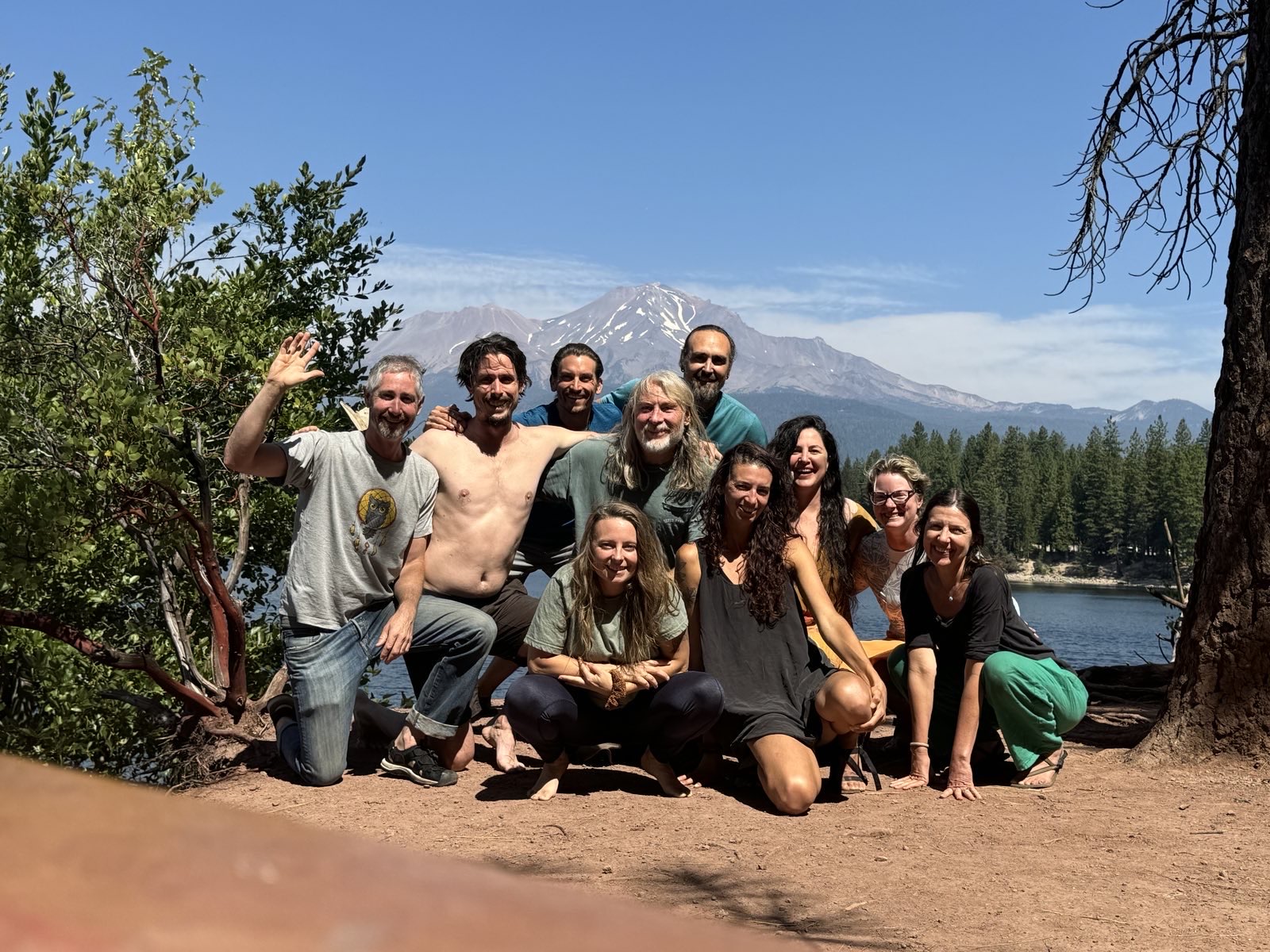 A group gathered by a mountain lake with Mount Shasta behind them
